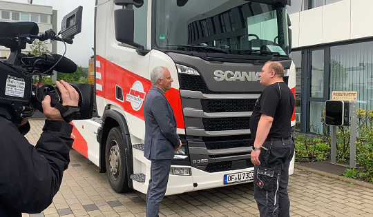 Kamerateam beim Dreh eines Mitarbeitergesprächs vor einem LKW